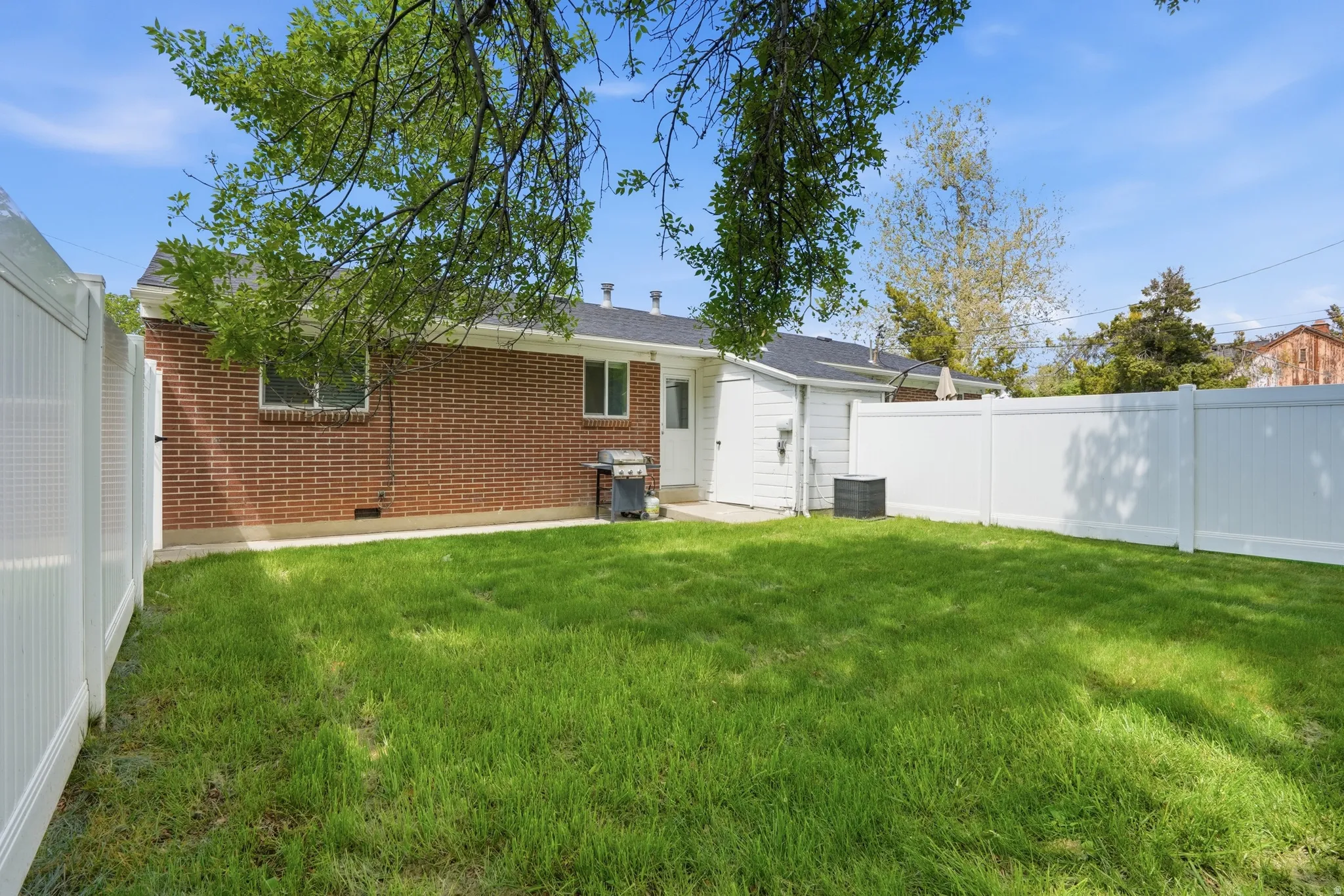 Rear view of house with a fenced backyard, brick siding, and crawl space