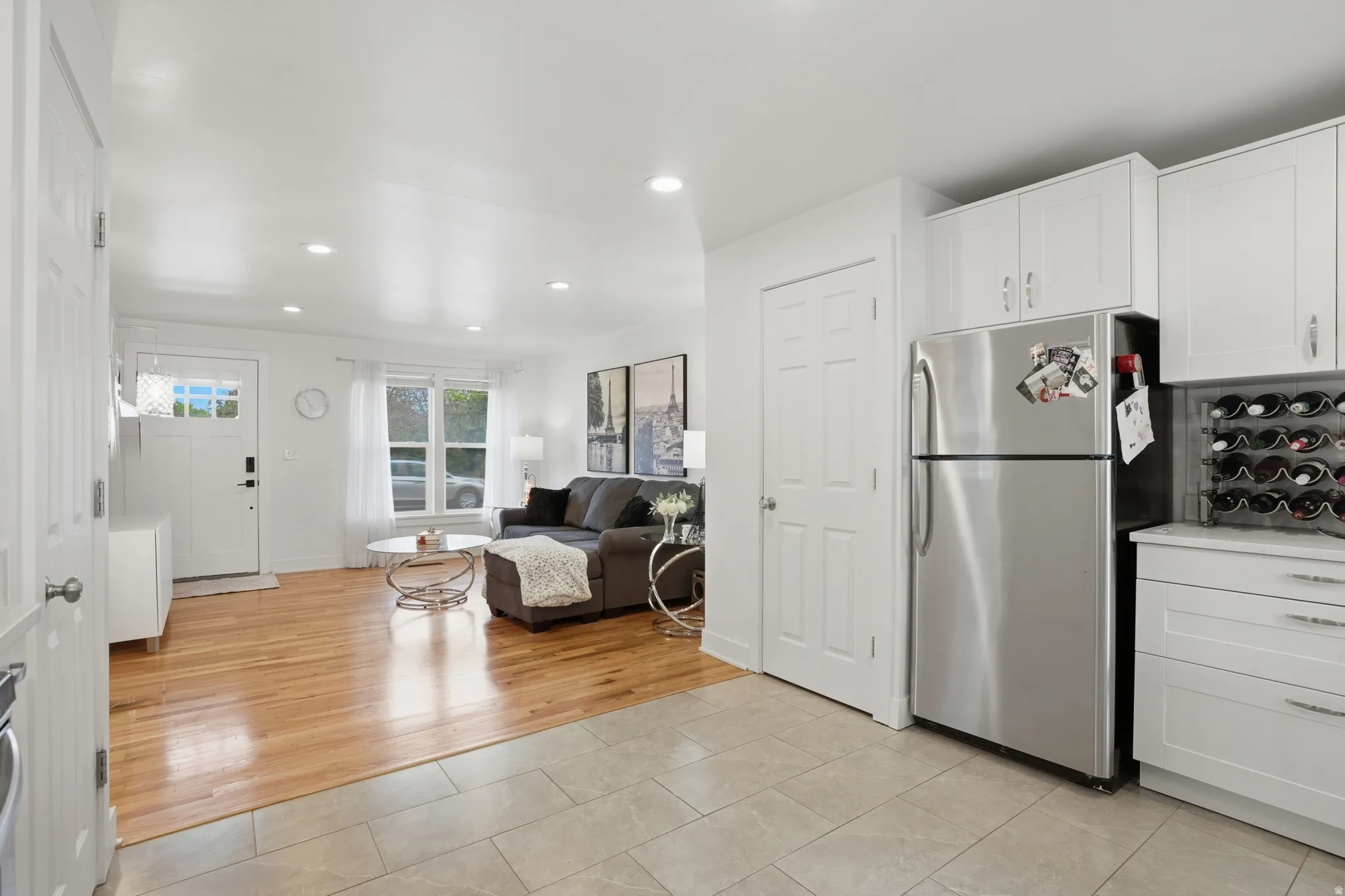 Kitchen with freestanding refrigerator, white cabinets, light tile patterned flooring, recessed lighting, and open floor plan