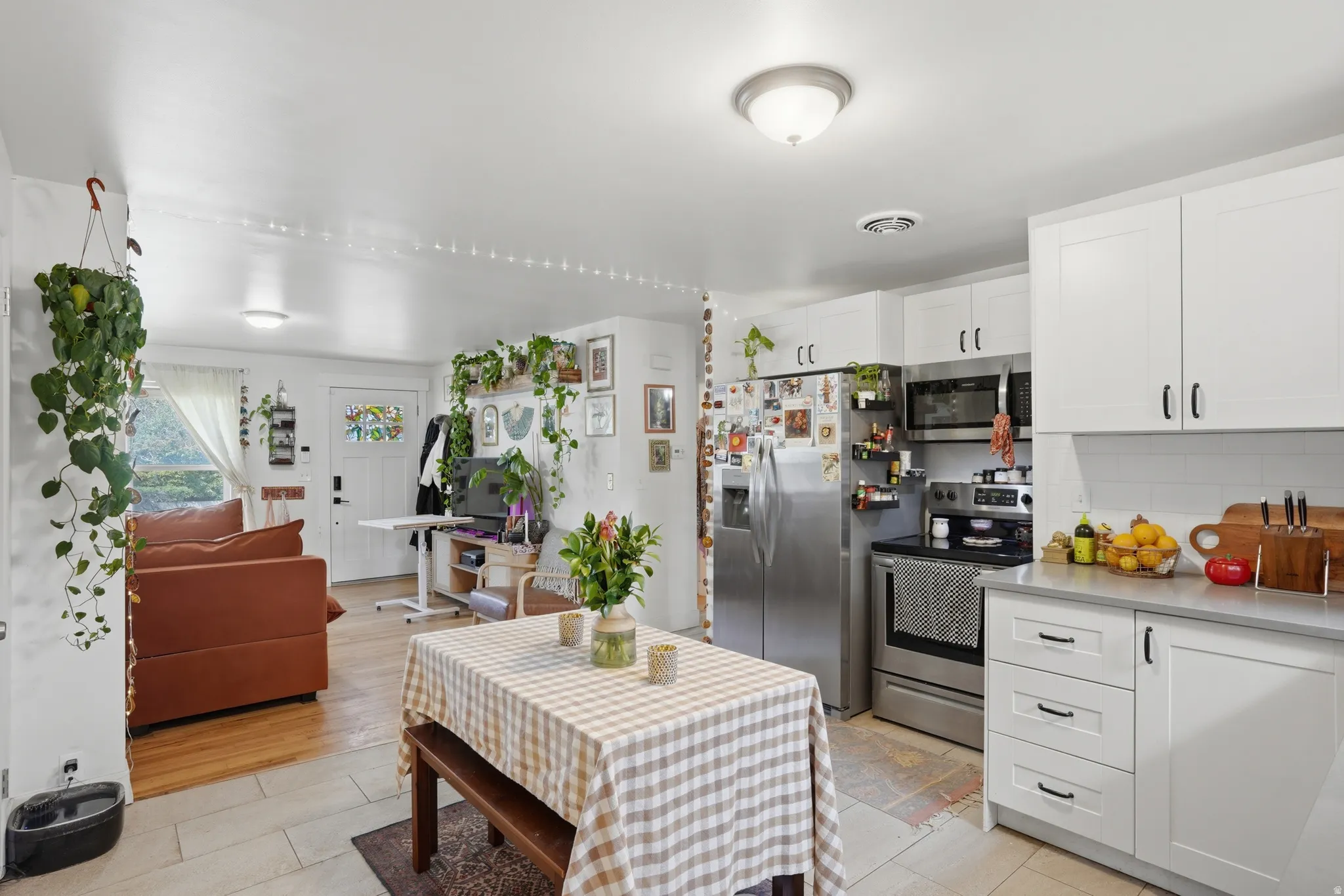Kitchen with stainless steel appliances, white cabinetry, open floor plan, and decorative backsplash