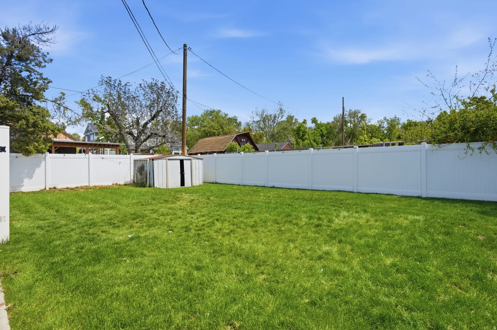 Fenced backyard featuring a storage shed