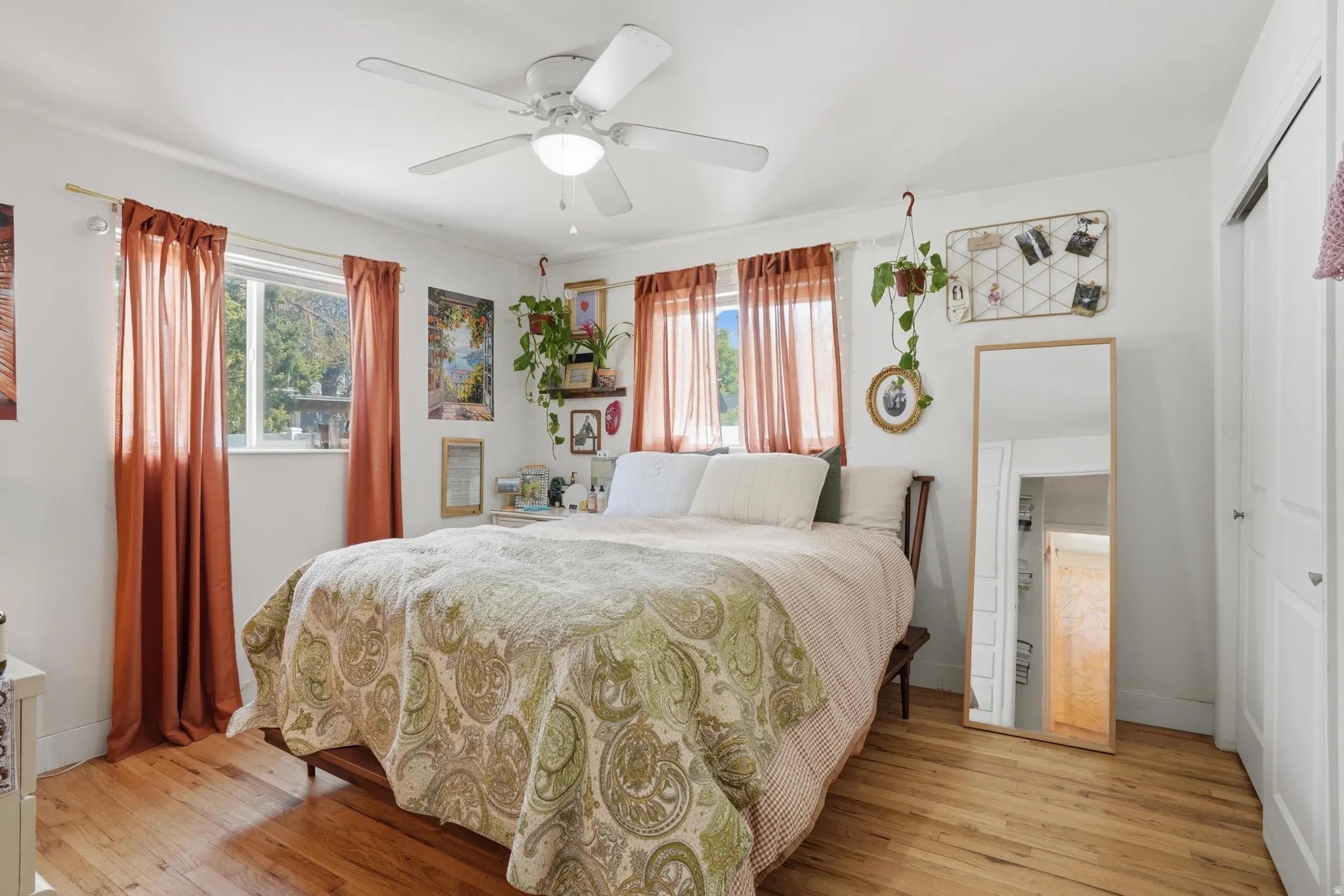 Bedroom with light wood-style floors, multiple windows, a closet, and ceiling fan