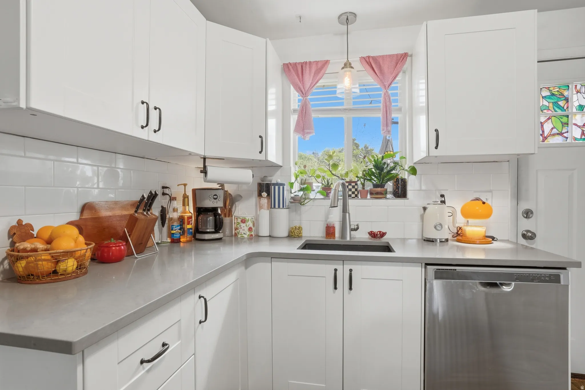 Kitchen with white cabinetry, dishwasher, and hanging light fixtures