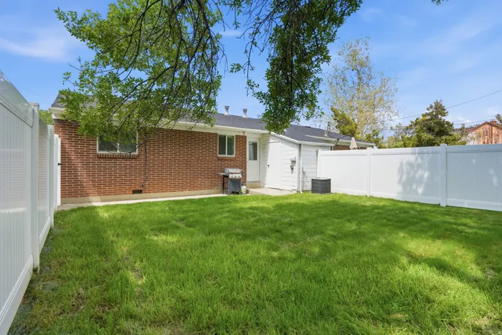 Rear view of house with a fenced backyard, brick siding, and crawl space