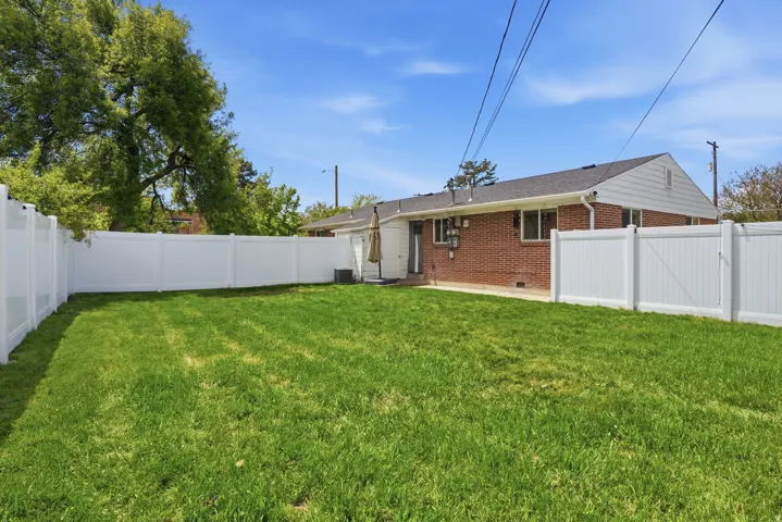 Rear view of house with brick siding, a fenced backyard, a patio, and crawl space