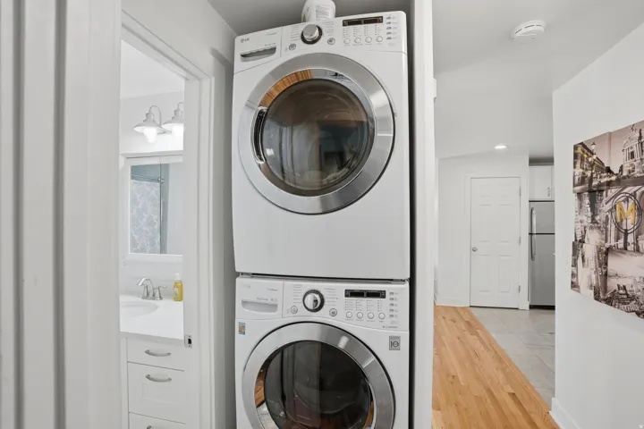Laundry area with stacked washing machine and dryer, light wood-type flooring, and recessed lighting