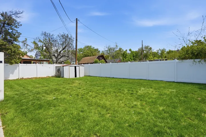 Fenced backyard featuring a storage shed