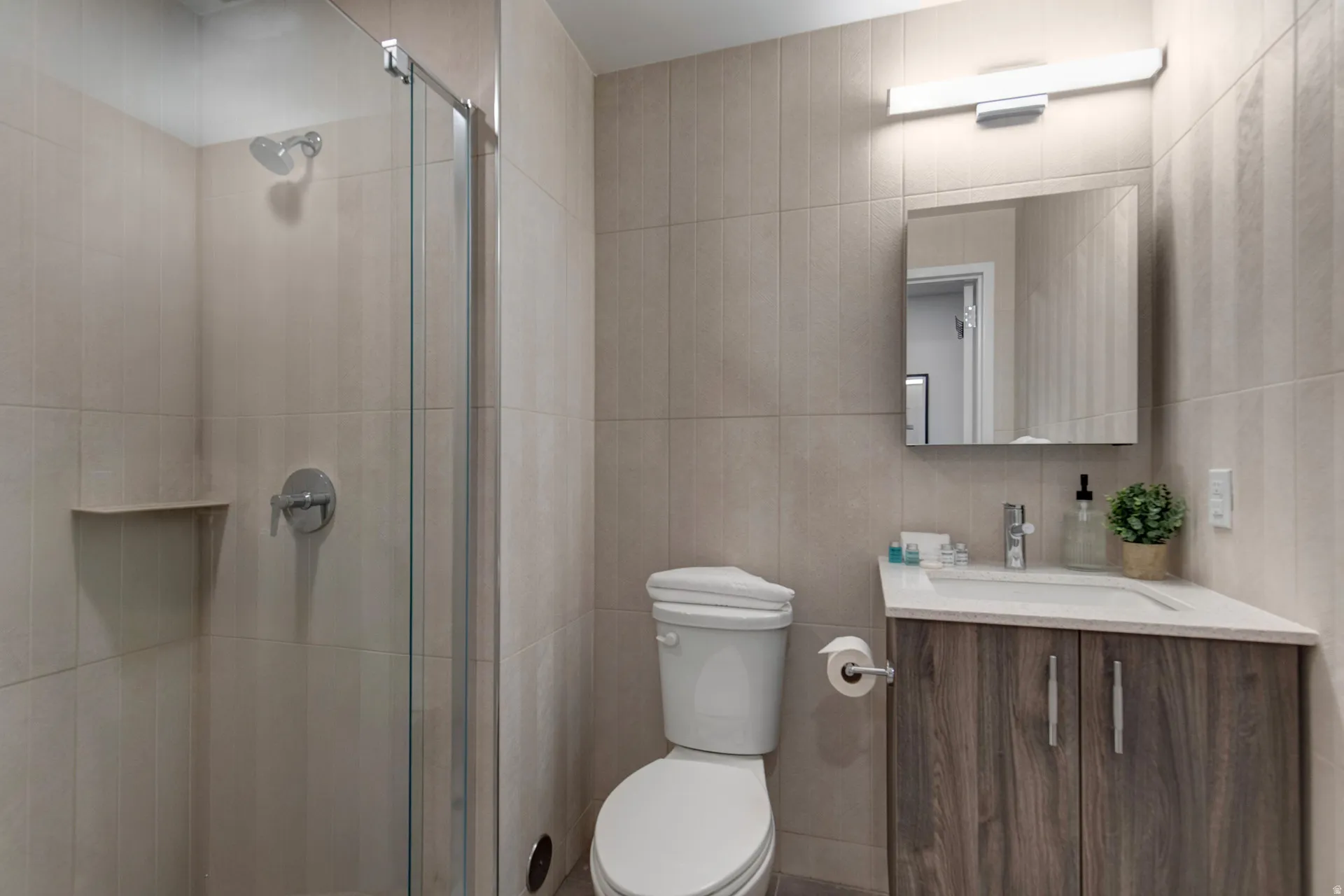 Full bathroom featuring vanity, a shower stall, and tile walls