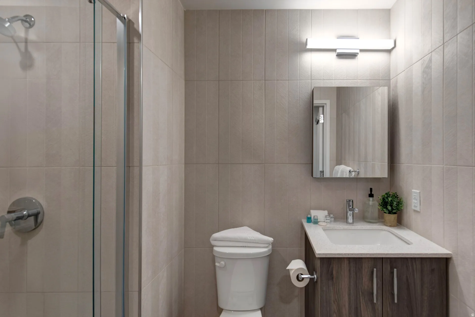 Full bath featuring vanity, a stall shower, and tile walls