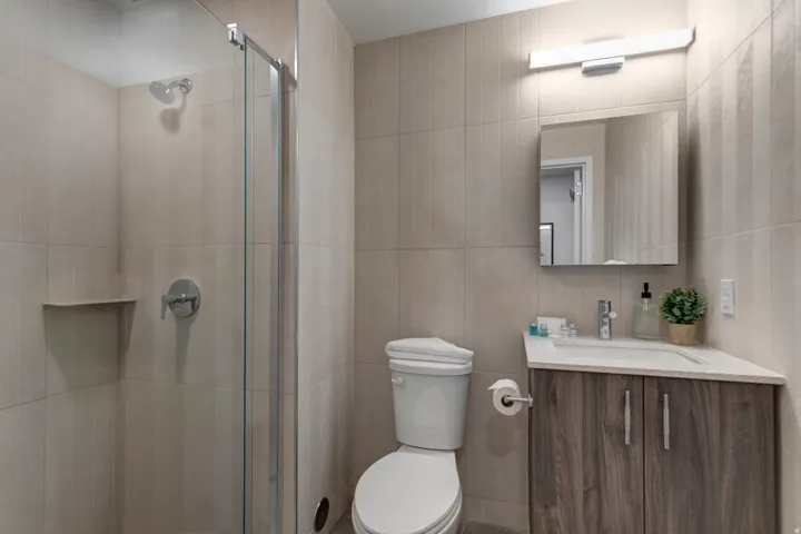 Full bathroom featuring vanity, a shower stall, and tile walls