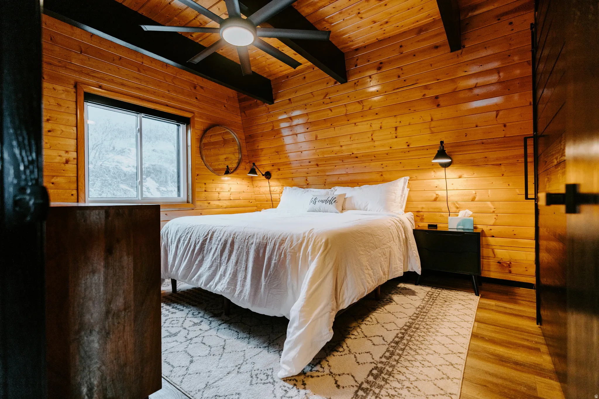 Bedroom featuring wood walls, a wood ceiling with exposed beams, light wood-style floors, and a ceiling fan