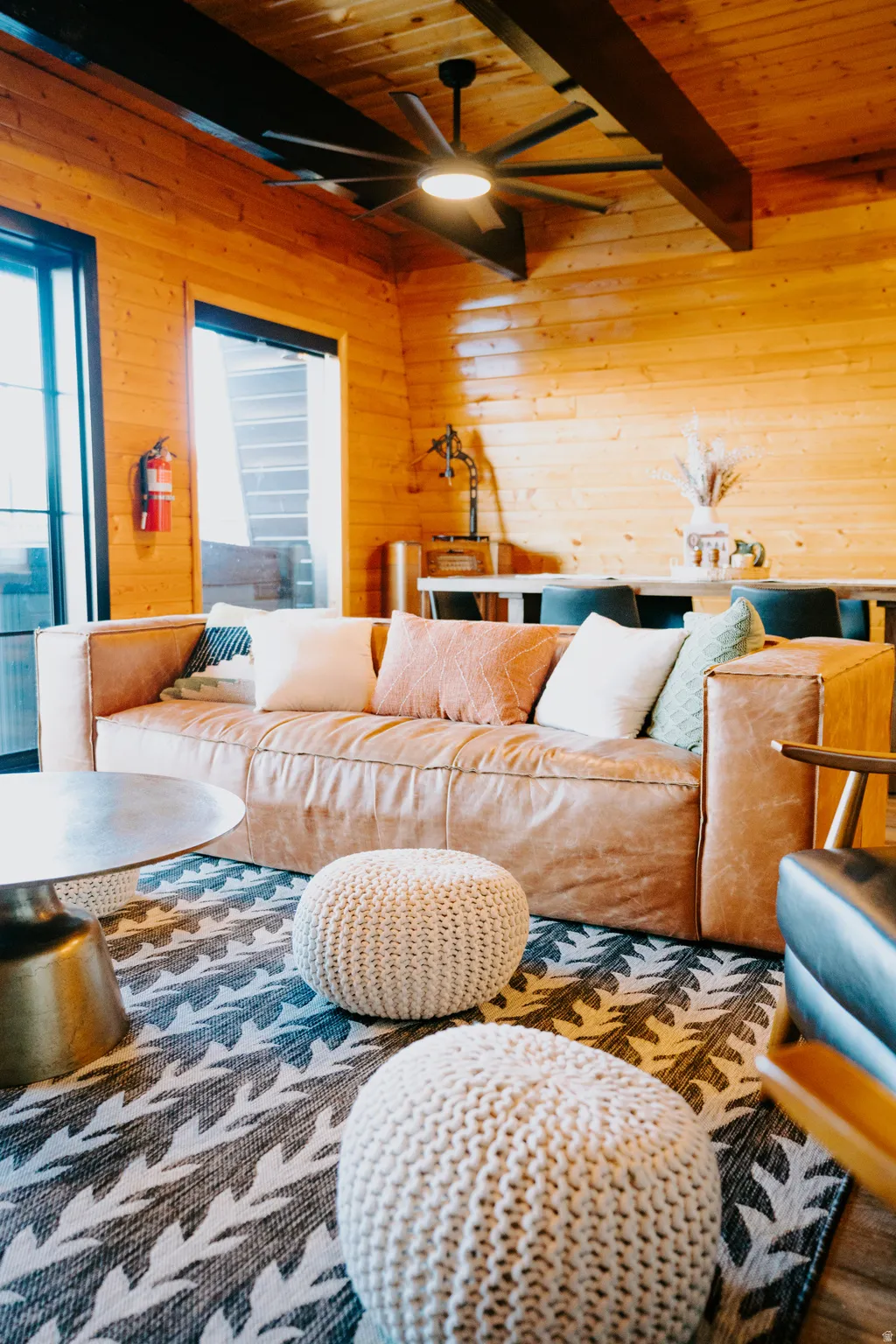 Living room with wooden walls, a wood ceiling with exposed beams, and a ceiling fan