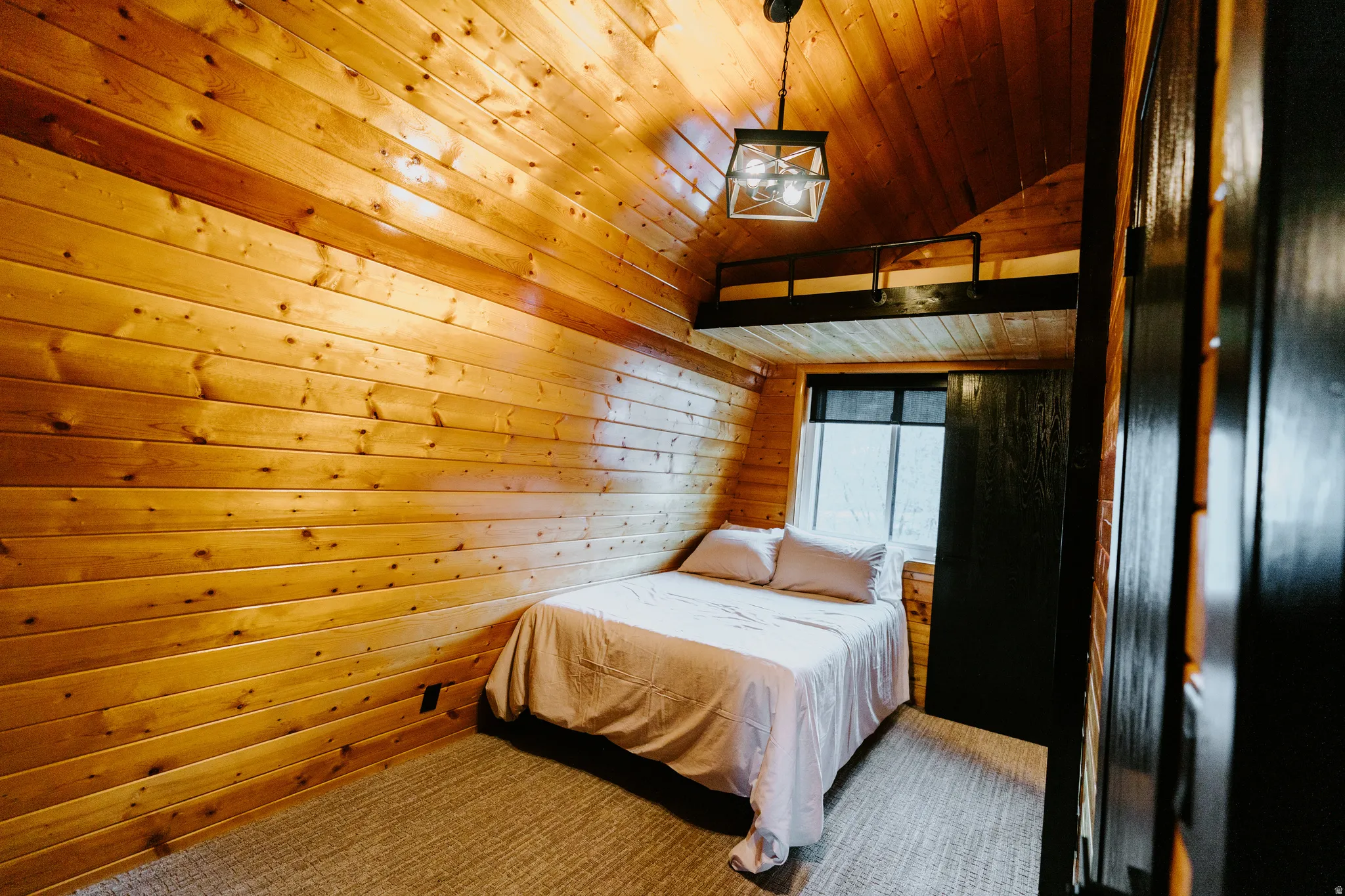 Bedroom with a vaulted wooden ceiling and wood walls