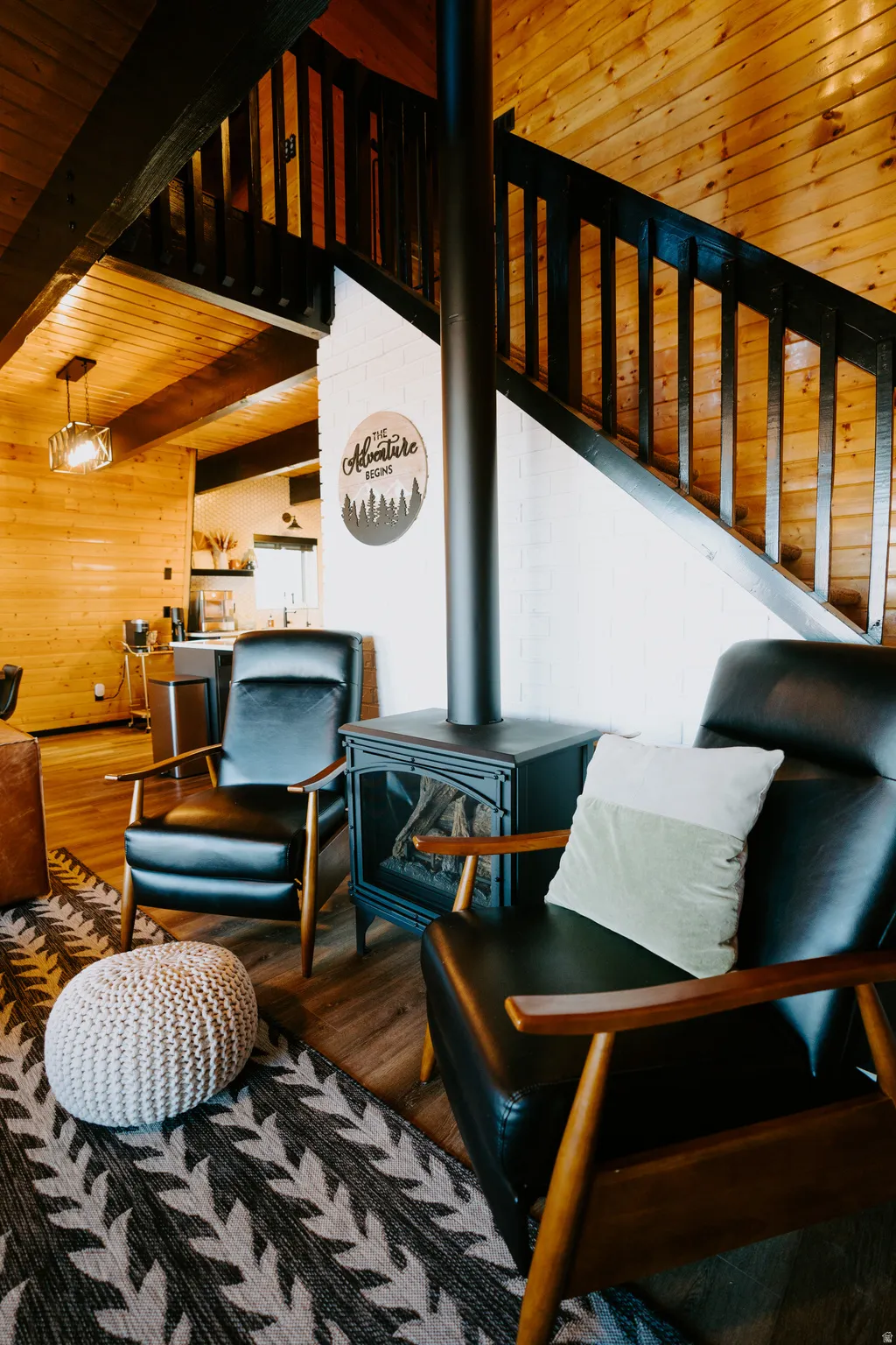 Living area with a wood stove, a wooden ceiling with exposed beams, wood finished floors, and wooden walls