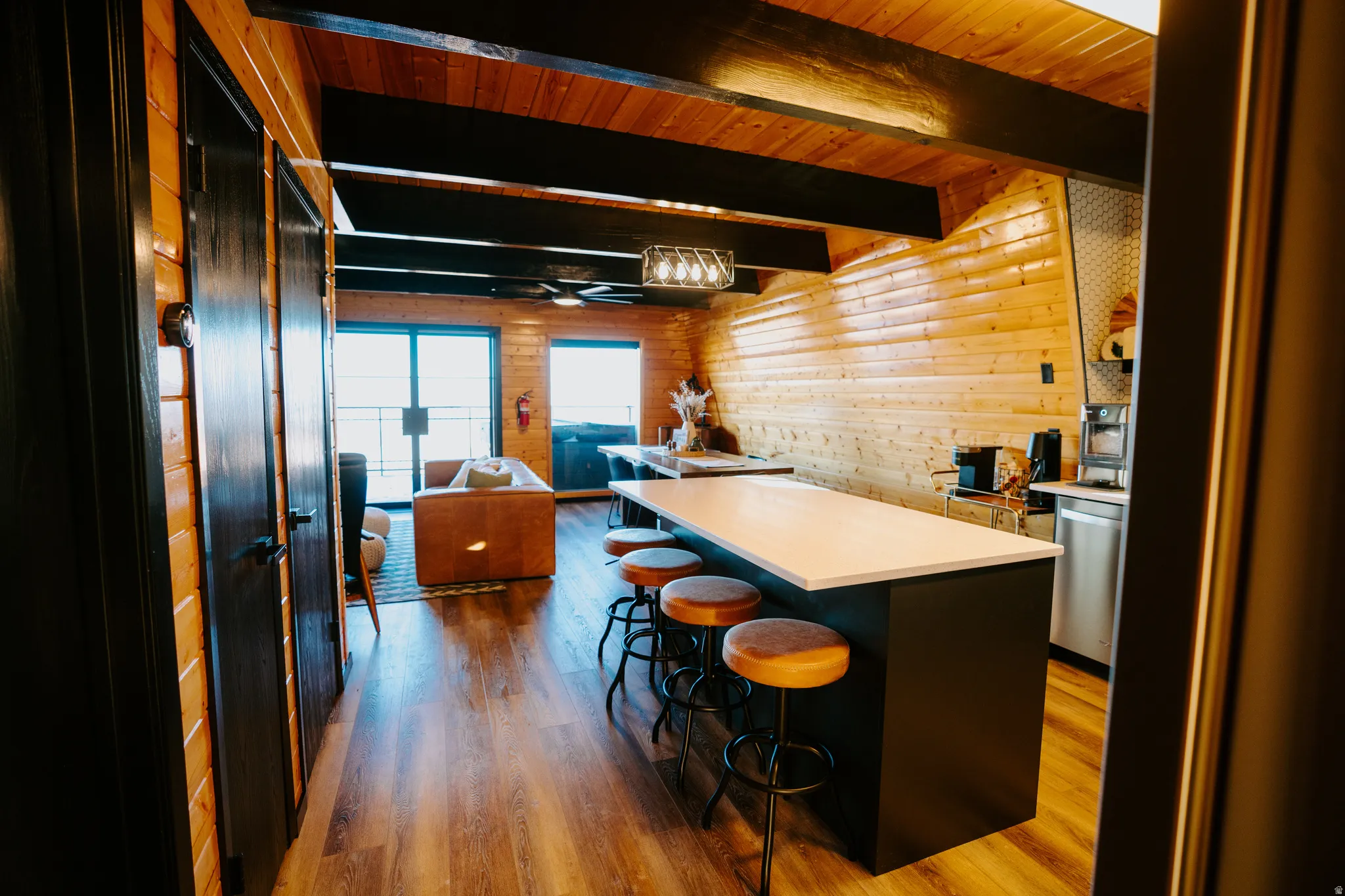 Kitchen with dark wood-style flooring, open floor plan, light countertops, a kitchen breakfast bar, and a wood ceiling with exposed beams