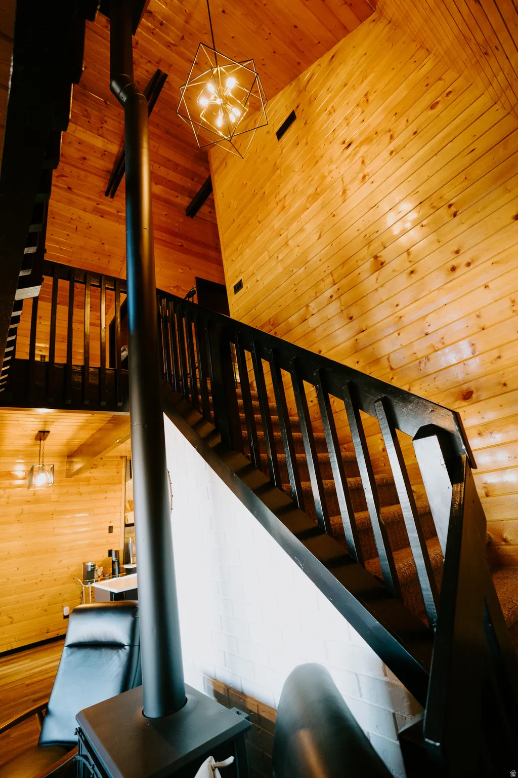 Stairs featuring wood walls, wood ceiling, a wood stove, and hanging lights