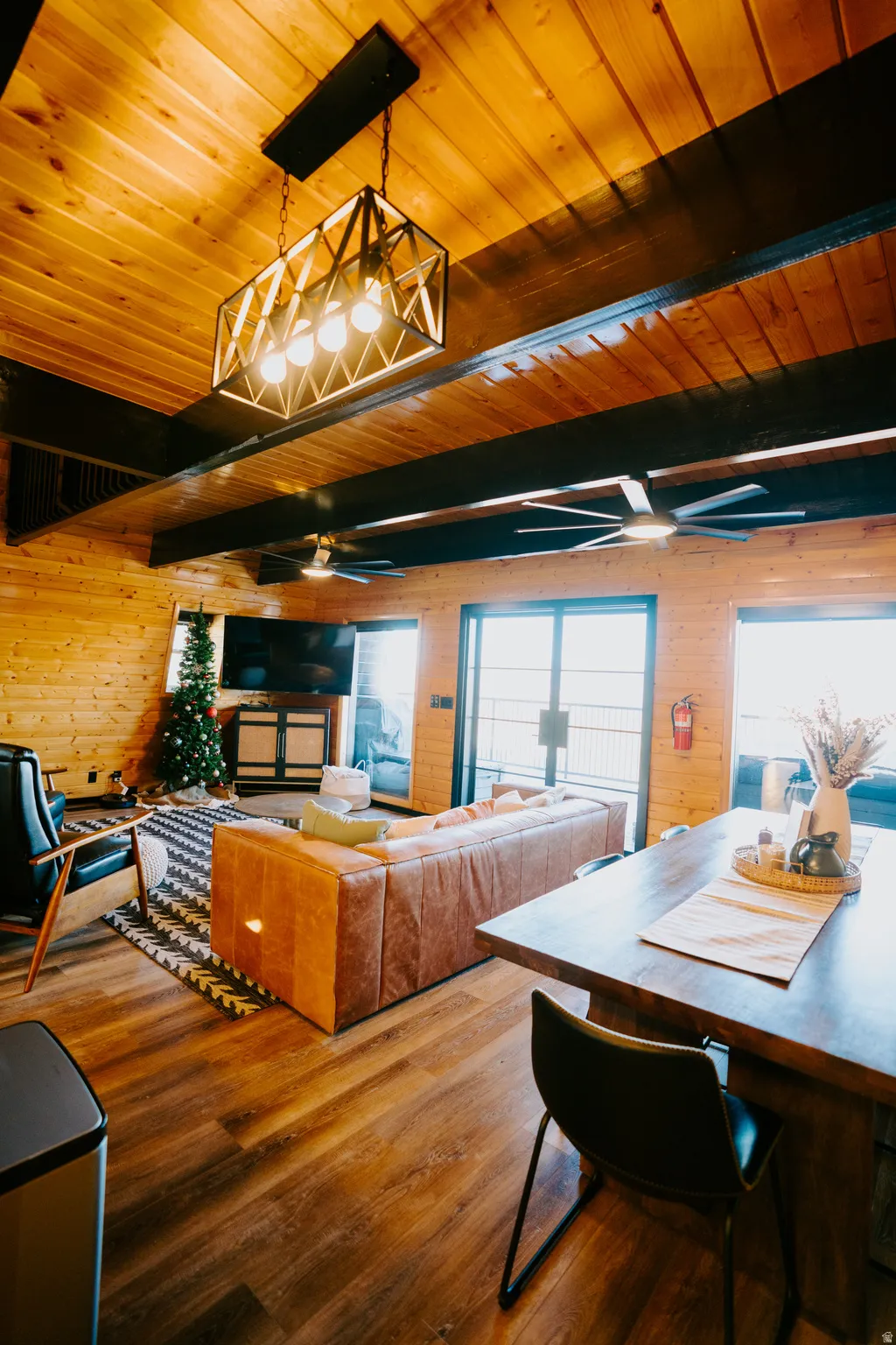 Dining area featuring wooden walls, wood-type flooring, a wood ceiling with exposed beams, and ceiling fan