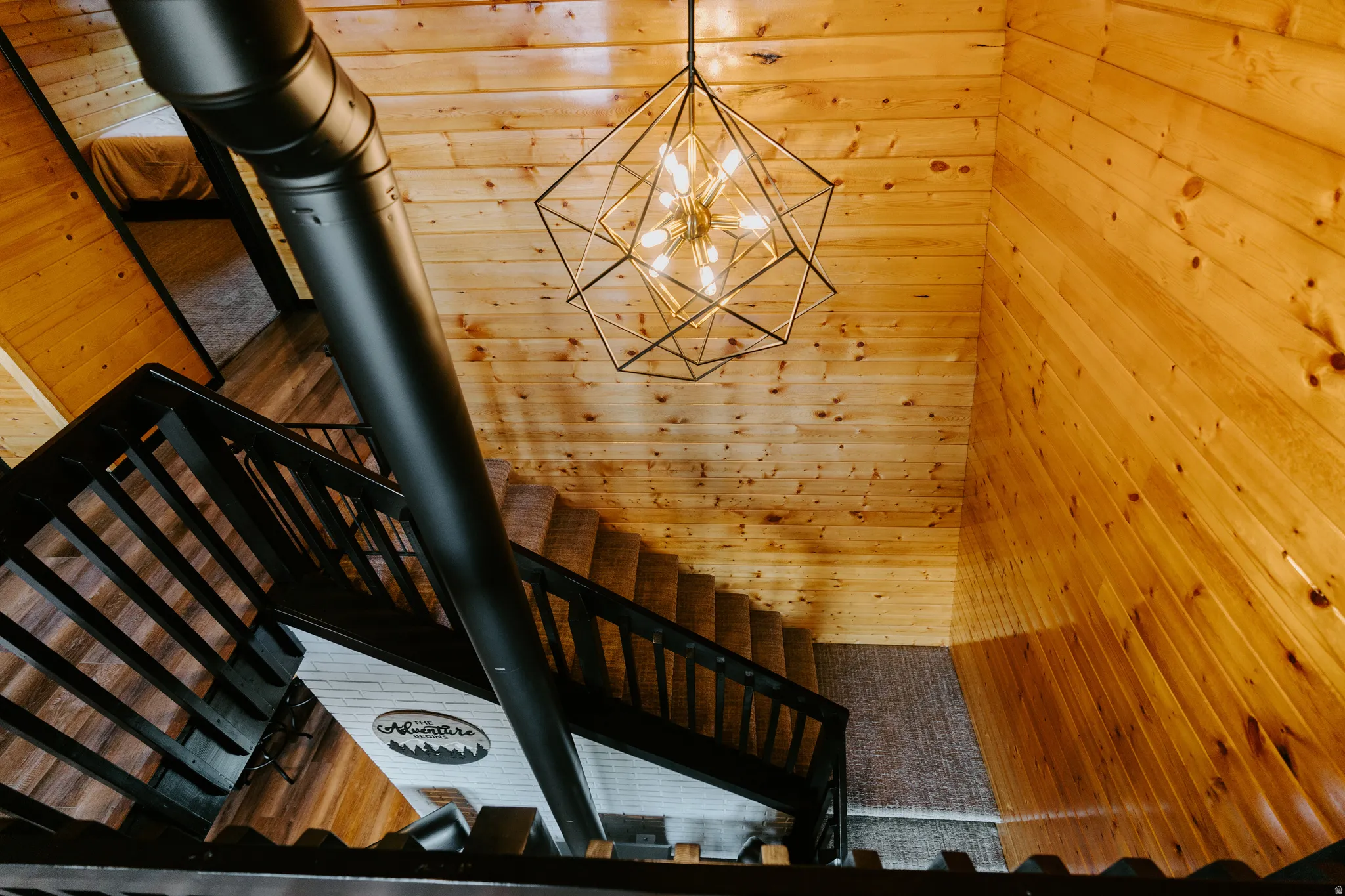 Stairs with hanging lights, wood walls, a wood stove, and a high ceiling