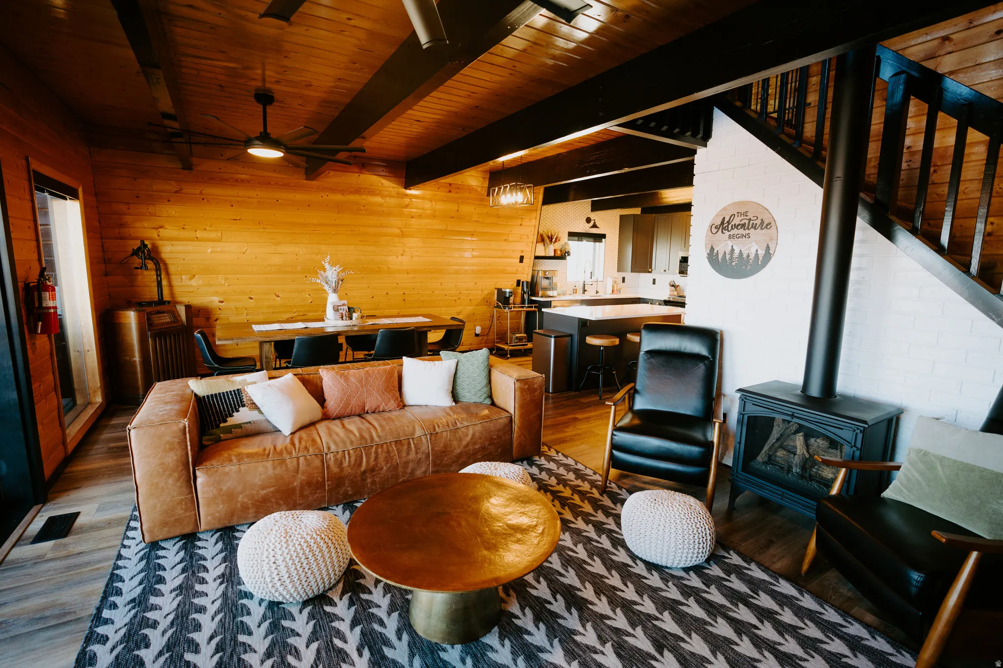 Living area featuring a wood stove, wood finished floors, wood walls, a wooden ceiling with exposed beams, and ceiling fan