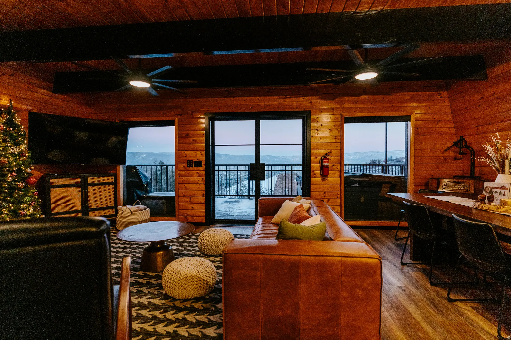 Living area featuring a ceiling fan, wood walls, dark wood finished floors, and a wood ceiling with exposed beams