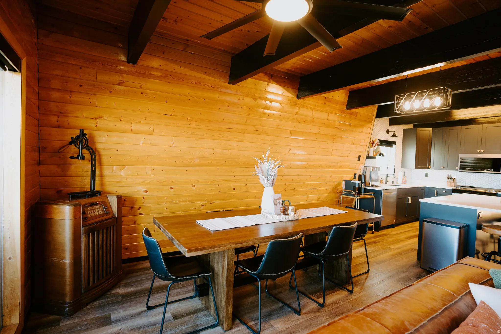 Dining area featuring a wooden ceiling with exposed beams, wood walls, light wood-style floors, and a ceiling fan