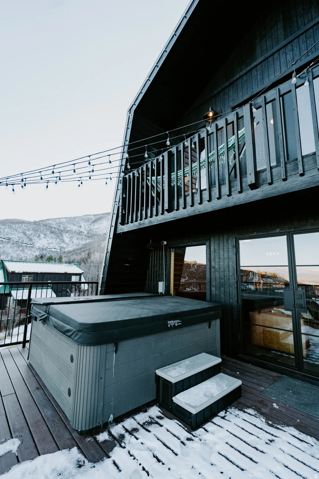 Snow covered deck with a hot tub and a mountain view