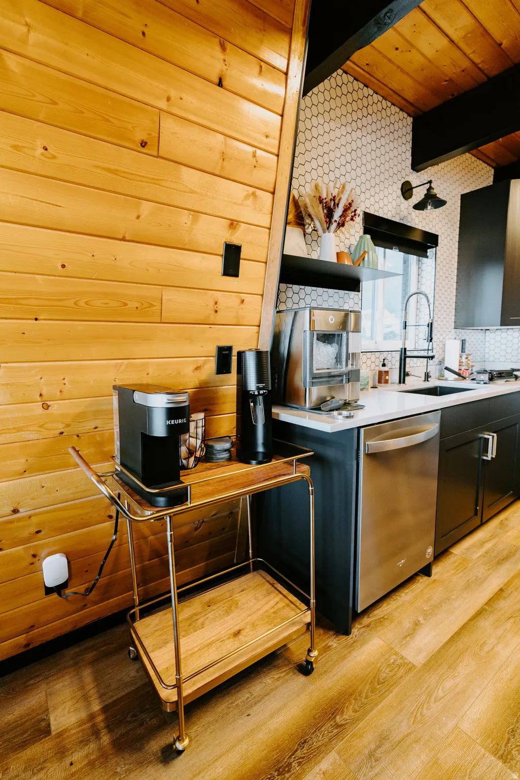 Kitchen with light wood finished floors, a wooden ceiling with exposed beams, dishwasher, and light stone countertops