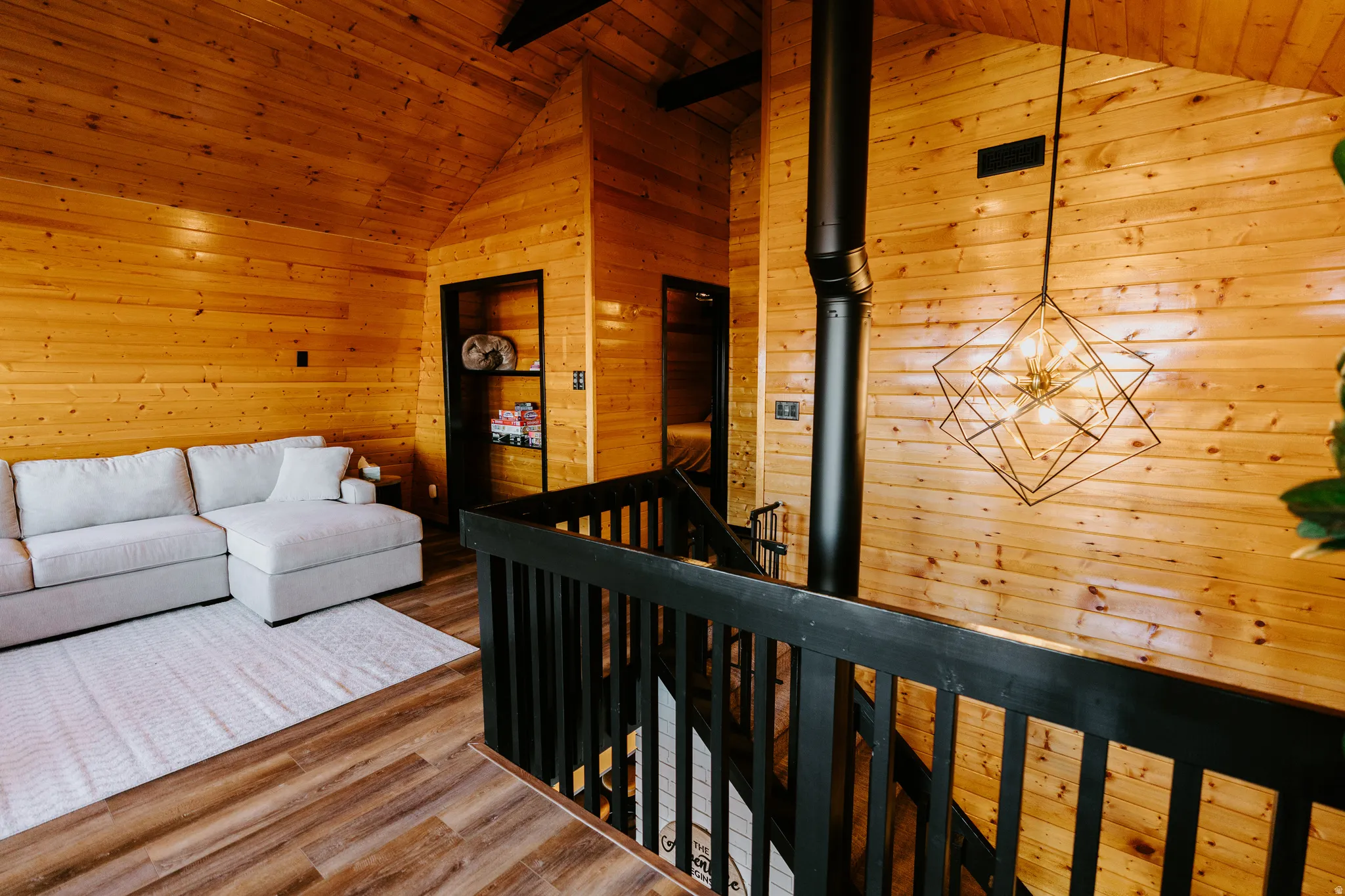 Living room with wood walls, a wooden ceiling with exposed beams, and wood finished floors
