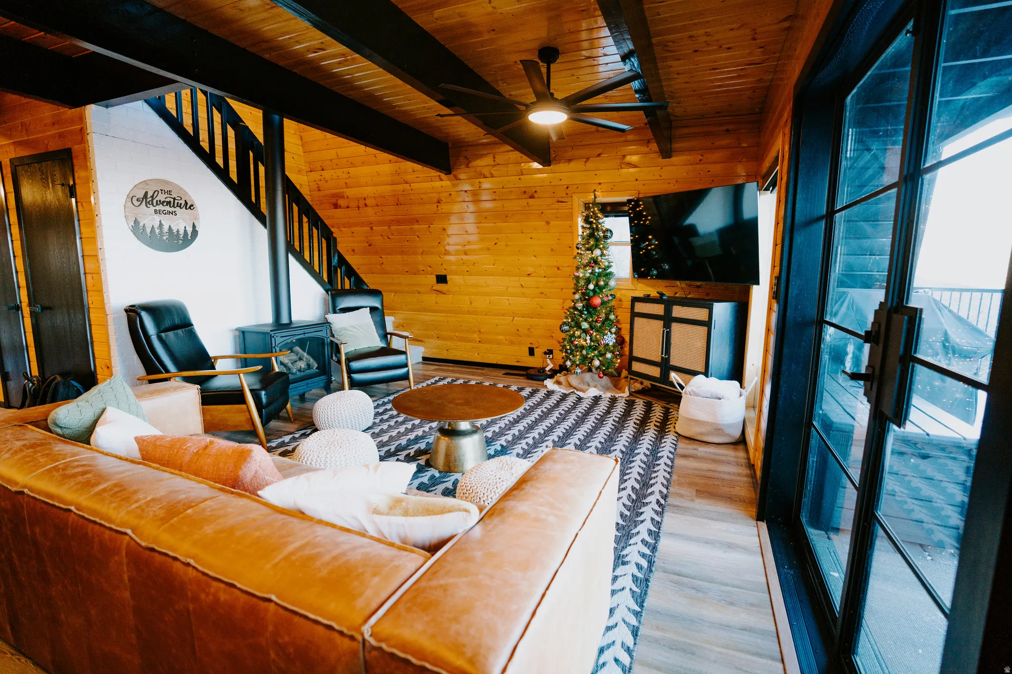 Living area featuring wood walls, a ceiling fan, a wood ceiling with exposed beams, and wood finished floors