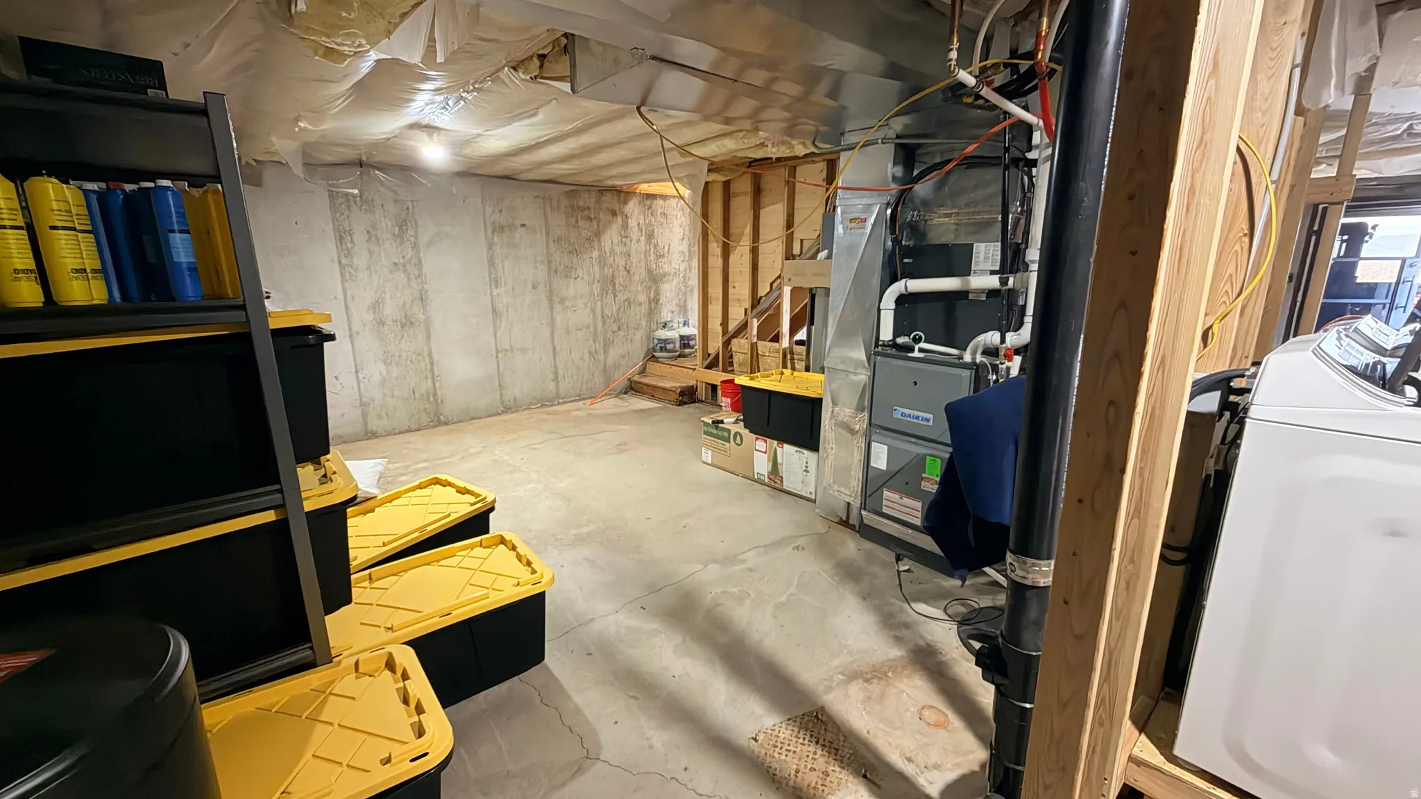 Unfinished below grade area with washer / dryer and heating unit