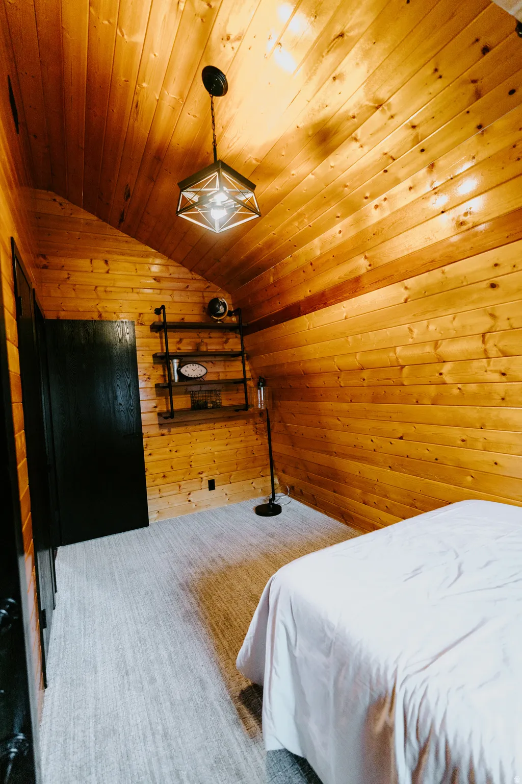 Bedroom with wood walls, a vaulted wooden ceiling, and carpet
