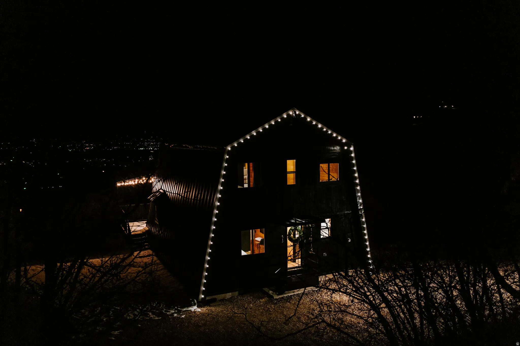 Back of house at twilight with a gambrel roof and a patio area