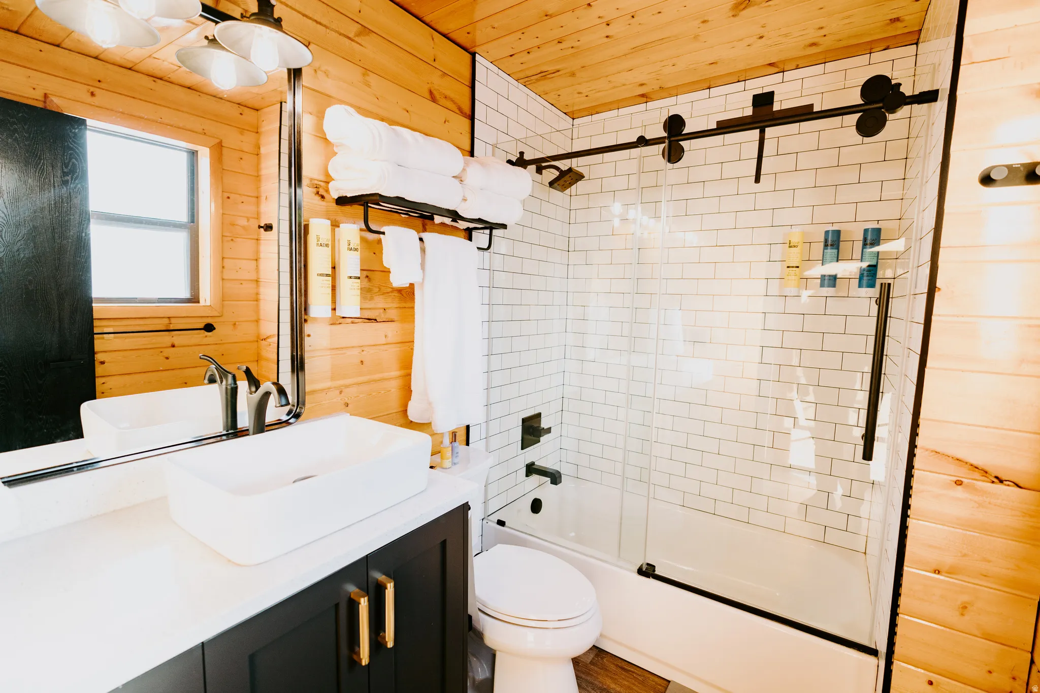 Full bath featuring wooden walls, enclosed tub / shower combo, vanity, and wood ceiling