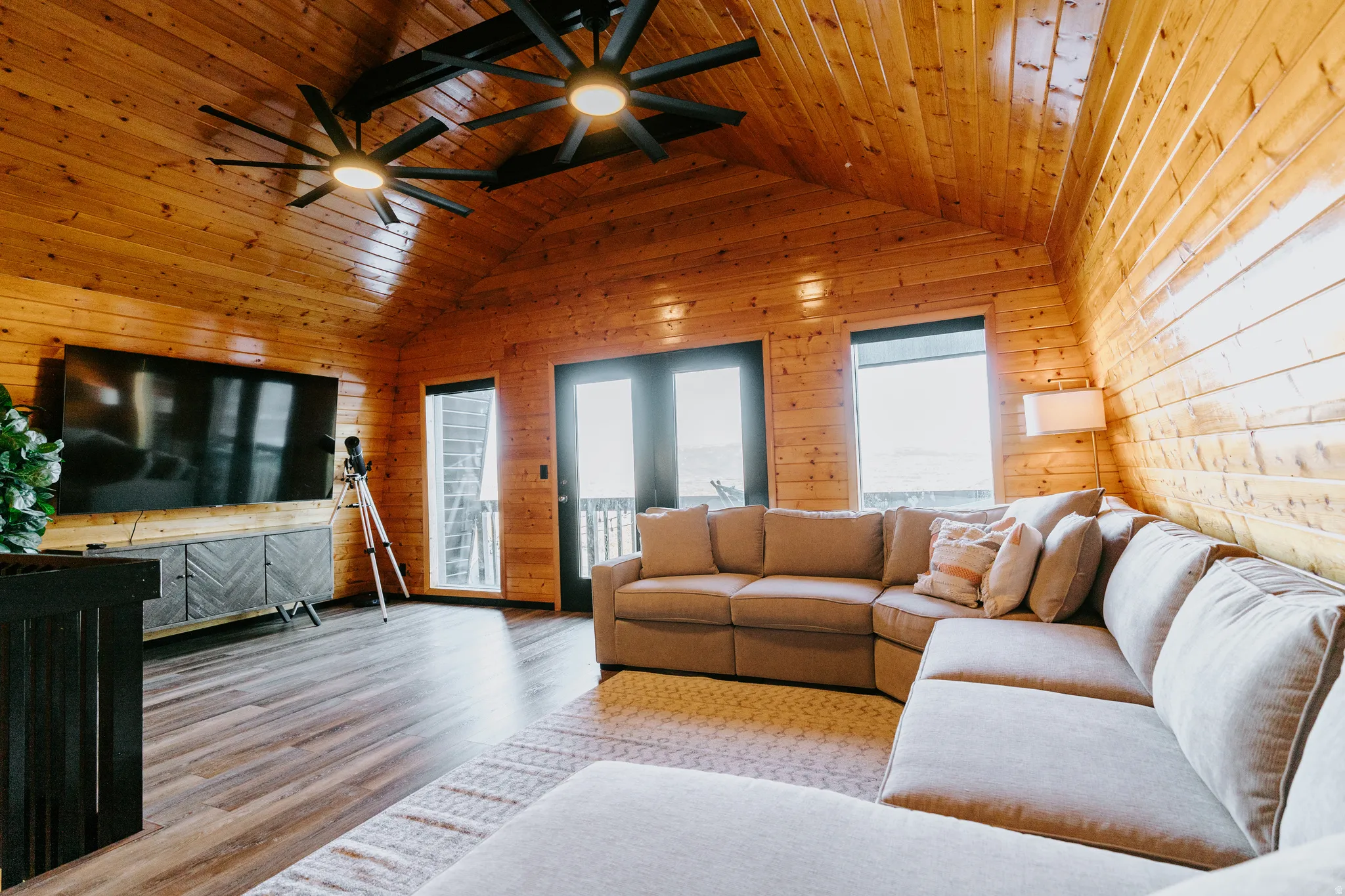 Living room featuring ceiling fan, wood finished floors, wooden walls, and wooden ceiling