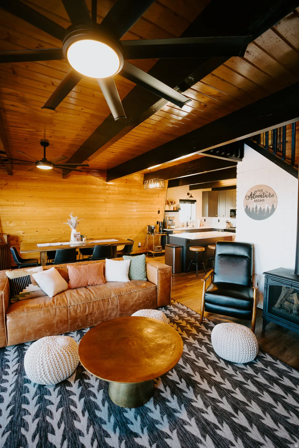 Living room with a wood stove, wood finished floors, a wooden ceiling with exposed beams, and wood walls