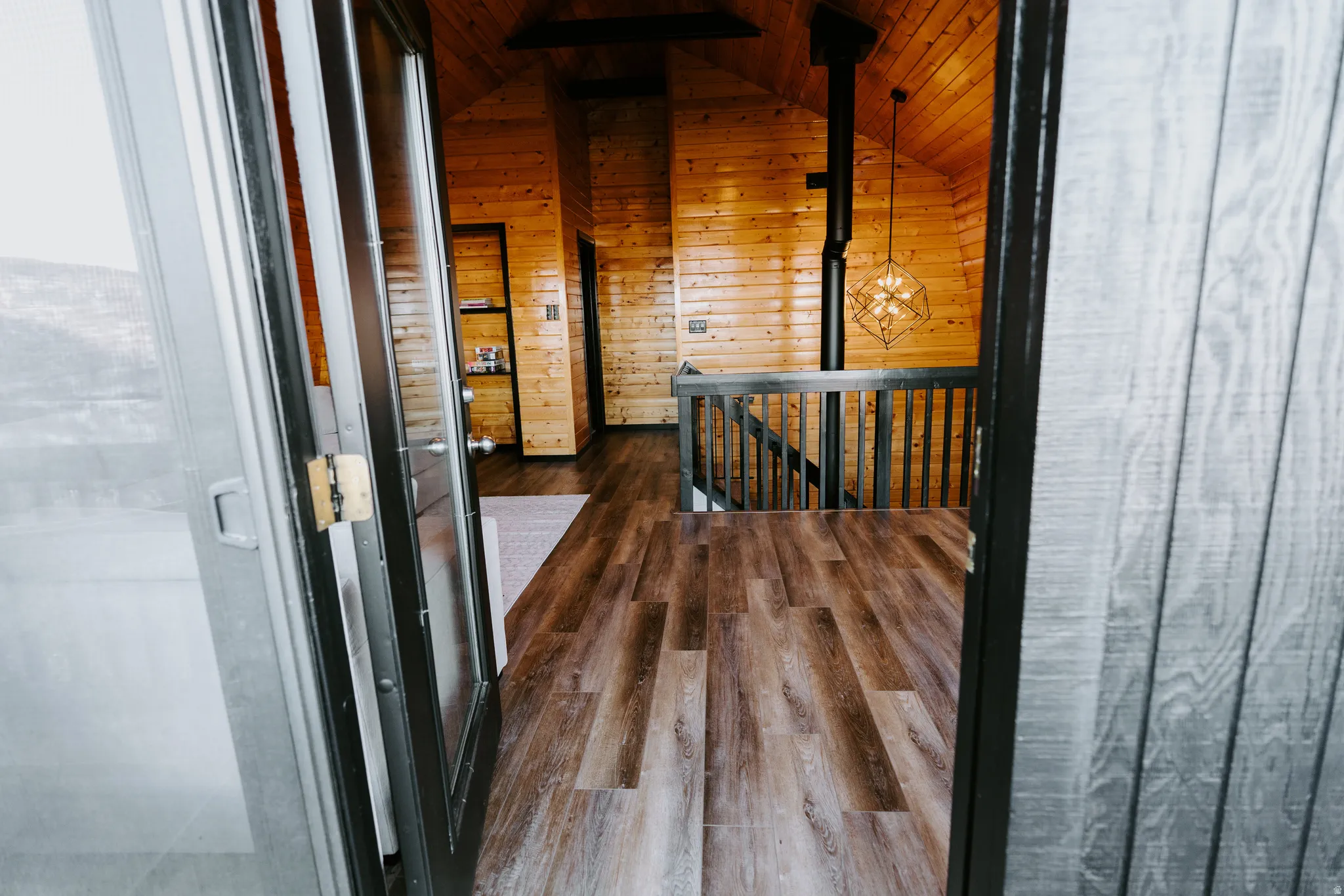 Hall featuring an upstairs landing, wooden ceiling, dark wood-style floors, and wood walls