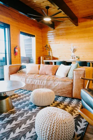 Living room with wooden walls, a wood ceiling with exposed beams, and a ceiling fan