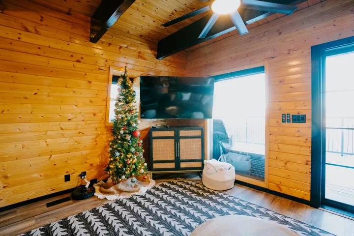 Sitting room with wooden walls, wood finished floors, ceiling fan, and a wooden ceiling with exposed beams