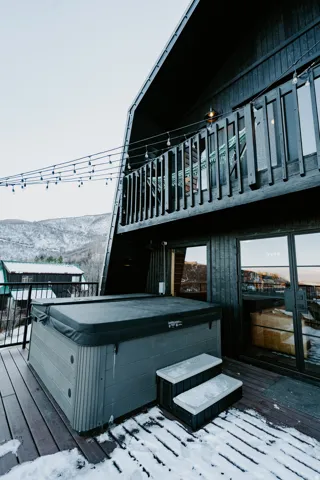 Snow covered deck with a hot tub and a mountain view