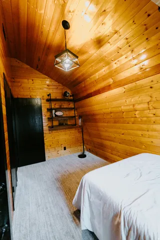 Bedroom with wood walls, a vaulted wooden ceiling, and carpet
