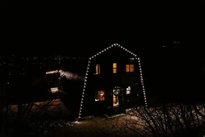 Back of house at twilight with a gambrel roof and a patio area