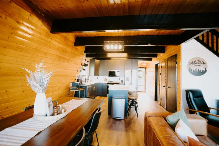 Dining space featuring wooden walls, light wood finished floors, and a wooden ceiling with exposed beams