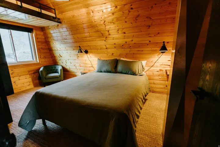 Carpeted bedroom featuring wood walls and a vaulted wooden ceiling