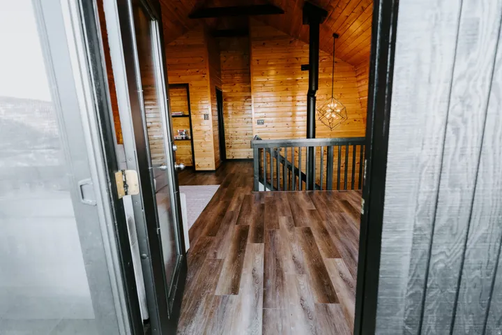 Hall featuring an upstairs landing, wooden ceiling, dark wood-style floors, and wood walls