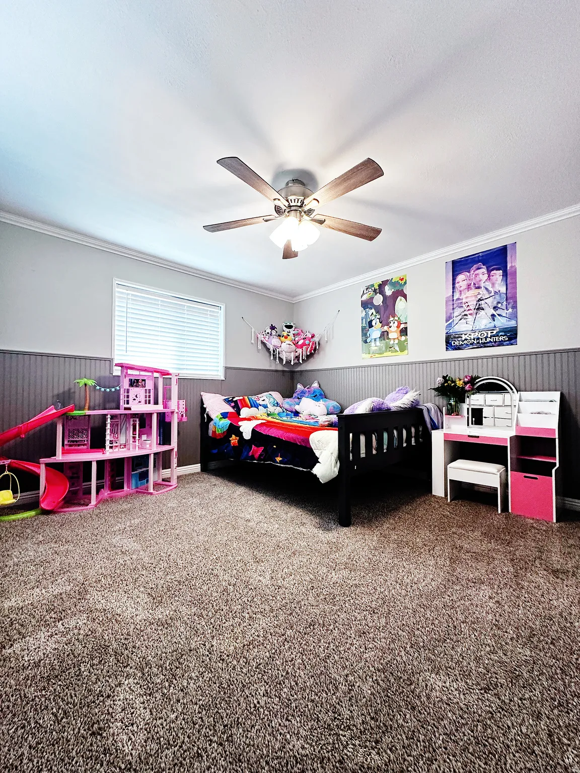 Carpeted bedroom with a wainscoted wall, a ceiling fan, ornamental molding, and wood walls