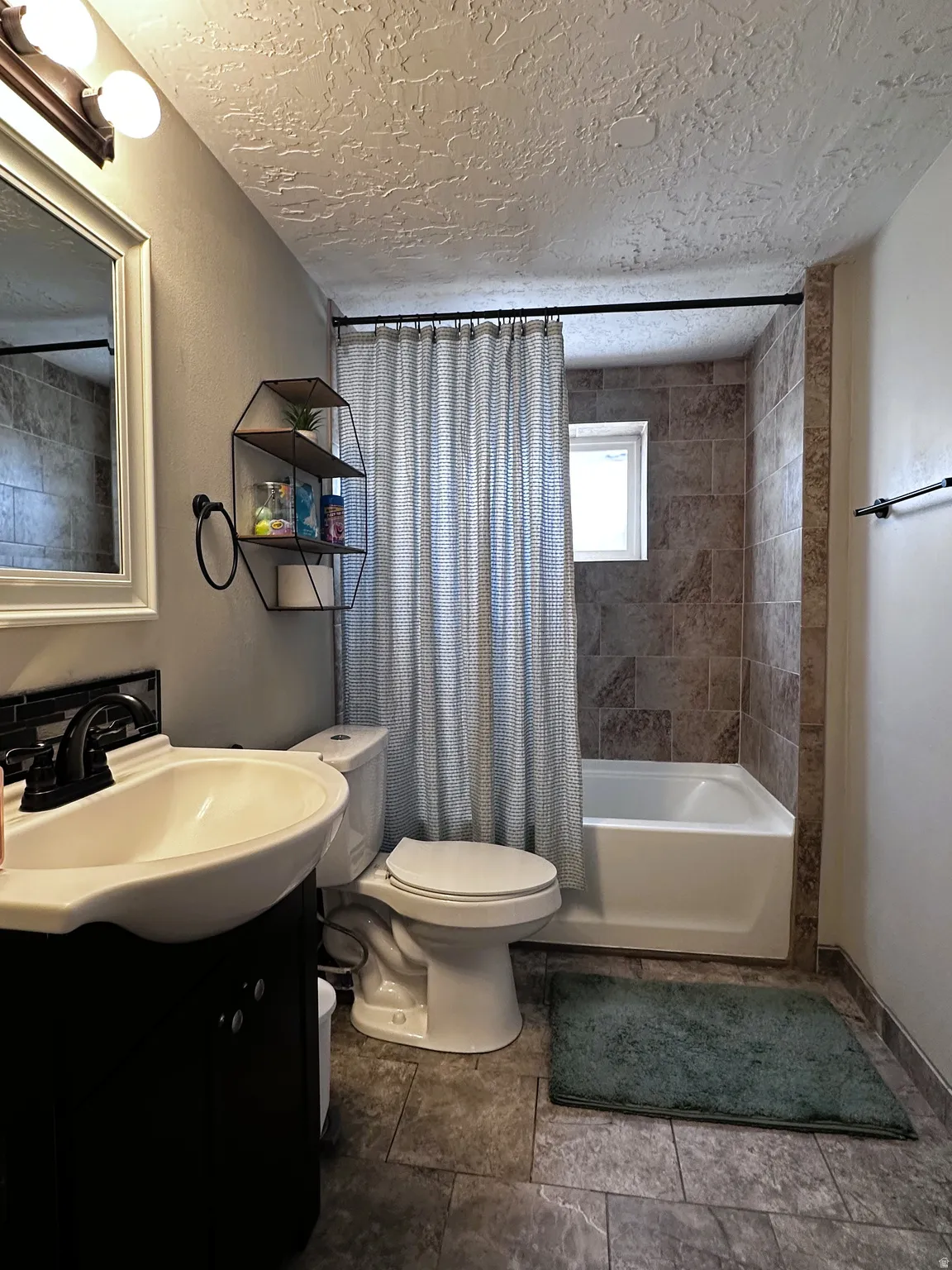 Bathroom featuring a freestanding sink, shower / tub combo located in the basement