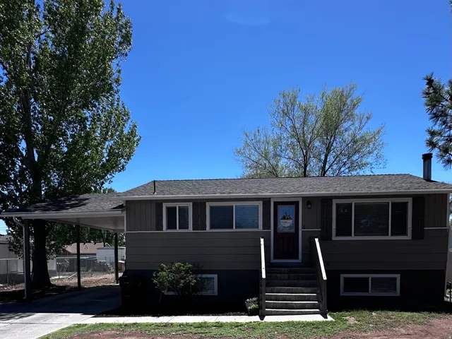 View of front of house with a shingled roof, a carport, concrete driveway, and entry steps