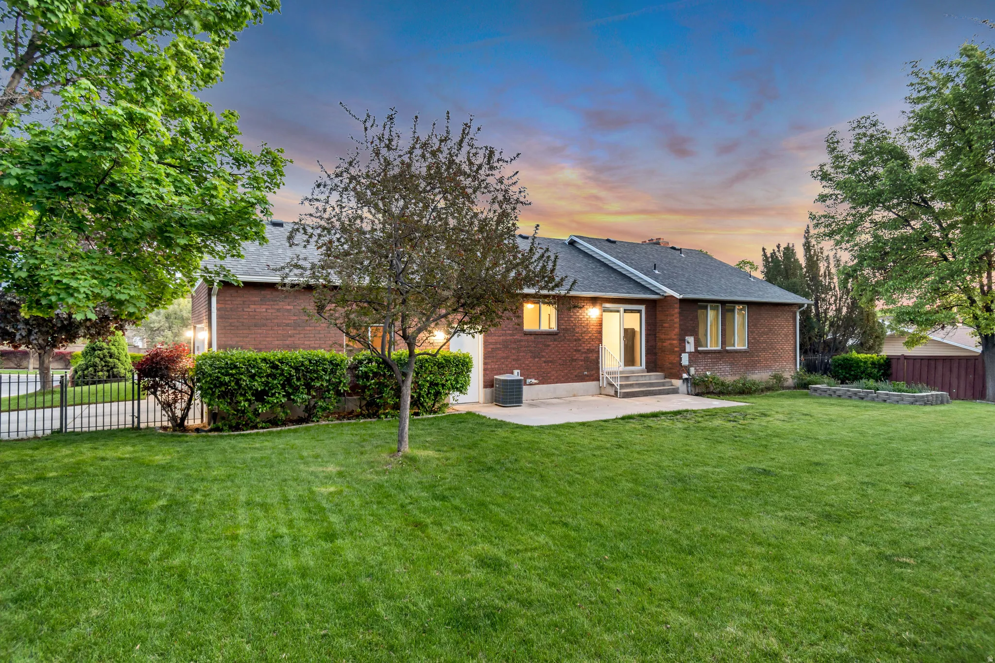 Expansive lawn featuring mature trees and a brick exterior home with a dark shingle roof