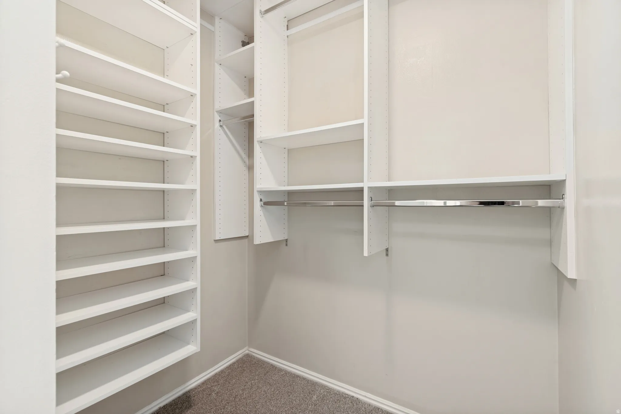 Custom closet system with multiple shelving units and chrome hanging rods