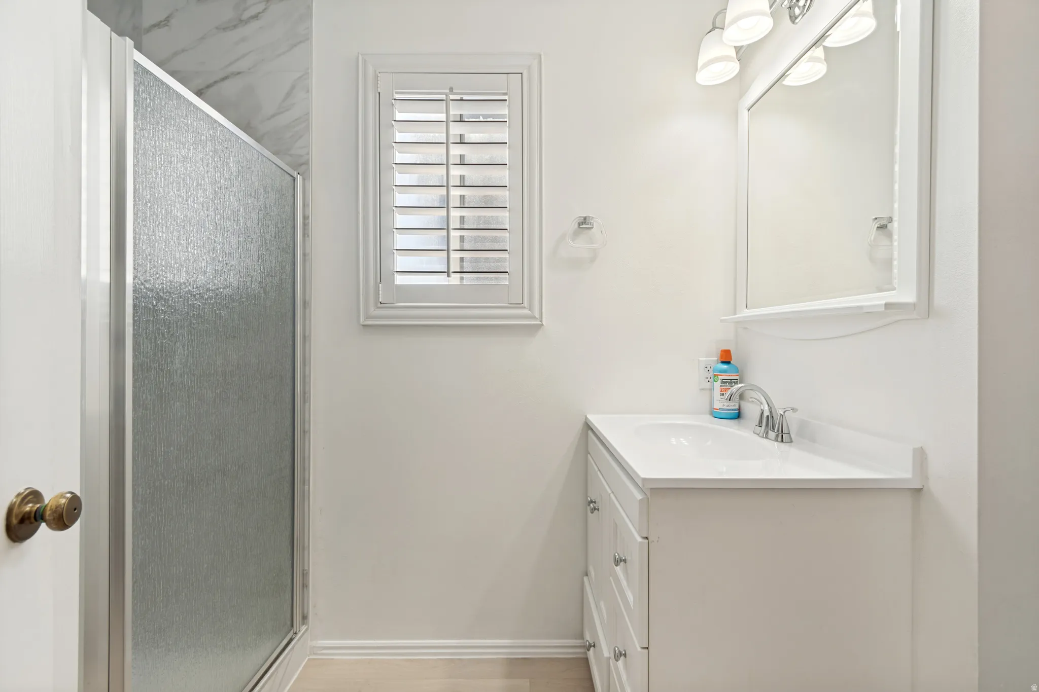 Bathroom featuring a white vanity with an integrated sink, polished chrome faucet, and mirrored medicine cabinet