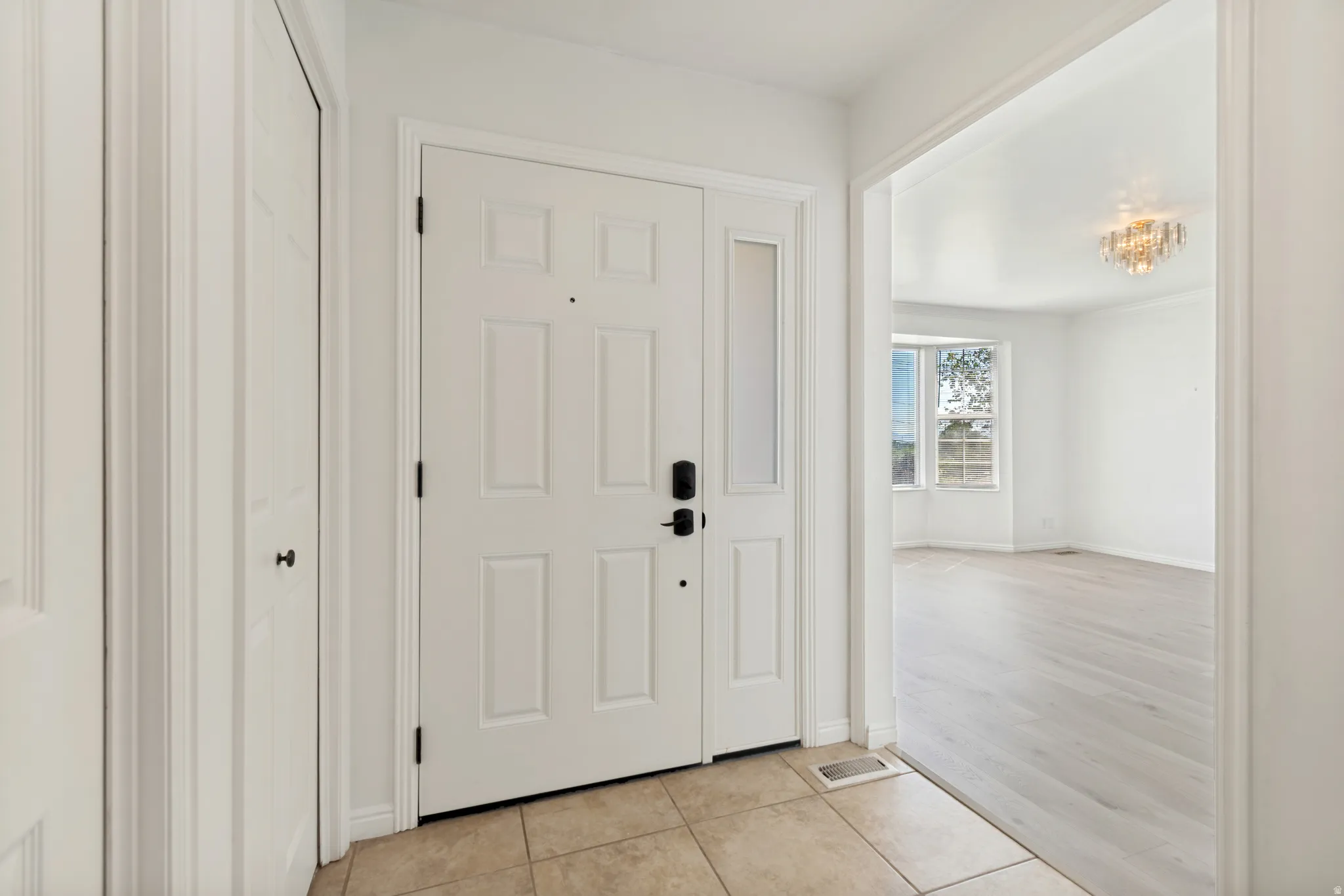 Entryway with neutral tile flooring, a paneled door featuring a smart lock, and a frosted sidelight